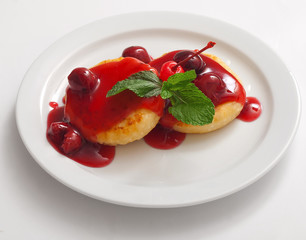 Cottage cheese pancakes with cherry jam on white plate.