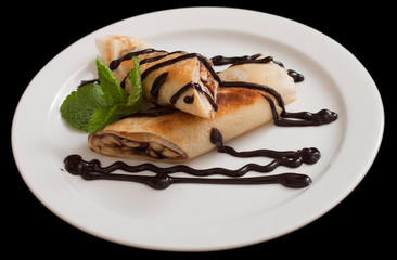 Plate of delicious crepes roll with fresh fruits and chocolate