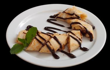 Plate of delicious crepes roll with fresh fruits and chocolate