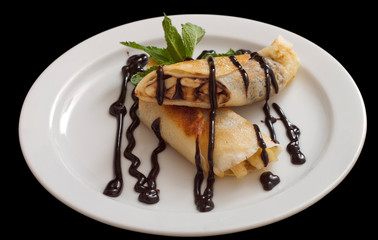 Plate of delicious crepes roll with fresh fruits and chocolate