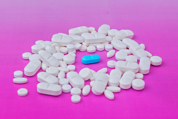 Obraz na płótnie Canvas white medicine pill on liht pink background and light blue in the center