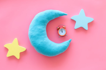 Night sleep concept with moon, stars toys and alarm clock on pink background top view