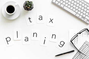 Tax planning copy on accountant work place with keyboard, coffee and glass on white desk background top view