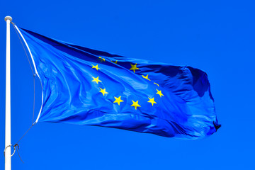 European Union Flag. EU Flag blowing in a wind on a blue sky background