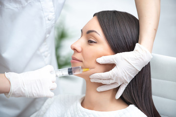 Filler injection for face. Plastic aesthetic facial surgery. Doctor woman giving injections with...