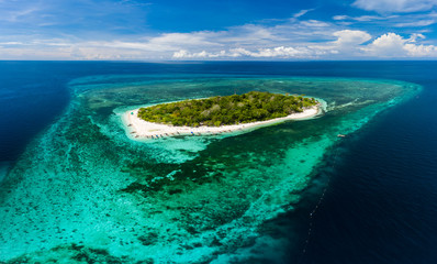 Aerial drone view of a beautiful tropical island surrounded by coral reef and deep ocean (Mantigue Island)