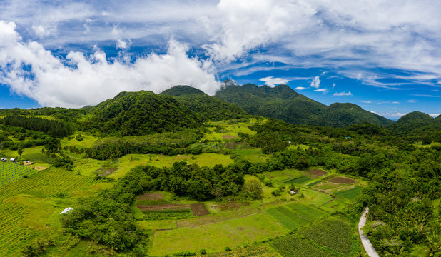 Aerial view of lush green farmland and clouds on the slopes of an active volcano (Mount Hibok-Hibok, Camiguin, Philippines)