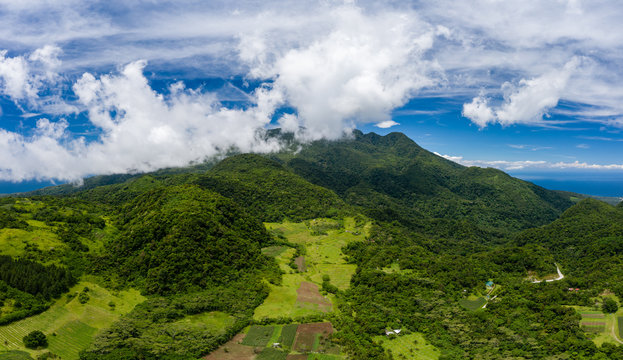 Aerial view of lush green farmland and clouds on the slopes of an active volcano (Mount Hibok-Hibok, Camiguin, Philippines)