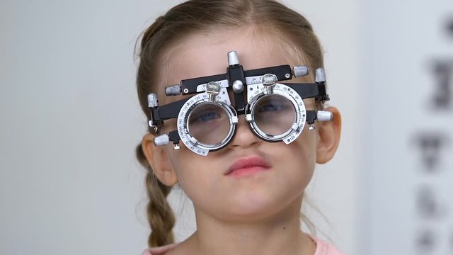 Sad schoolgirl in optical trial frame, eyesight testing, eyeglasses prescription