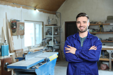 Young working man in uniform at carpentry shop, space for text