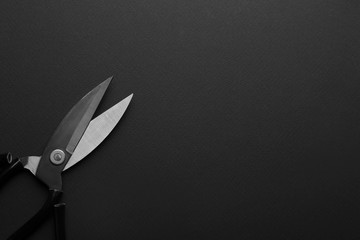 Pair of sharp scissors on dark background, top view. Space for text