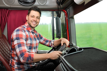 Professional driver sitting in cab of modern truck