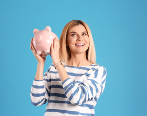 Woman with piggy bank on color background