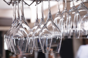 Set of empty clean glasses on bar racks