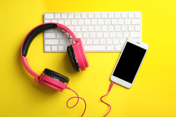 Modern headphones, phone and keyboard on color background, flat lay. Space for text