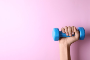 Woman holding vinyl dumbbell on color background, closeup with space for text