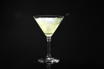 Glass of delicious cucumber martini on dark background