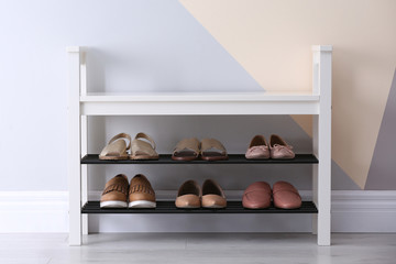 Shoe rack with different footwear near color wall, space for text. Stylish hallway interior - Powered by Adobe