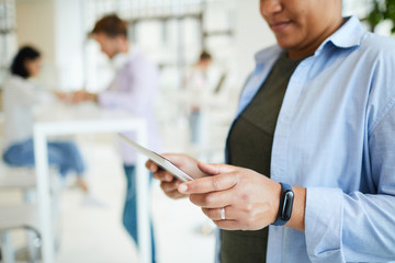 Close-up of portly black woman with fitness tracker using digital tablet while surfing net, copy space