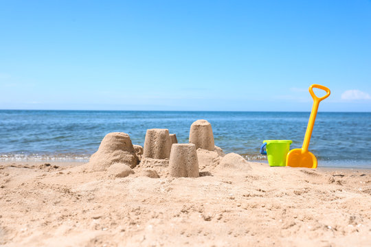 Little sand figures and plastic toys on beach near sea