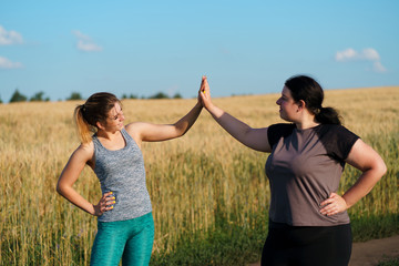 Friendship, personal trainer, group workout, weight loss, sports and health care. Two happy women friends give a five after jogging