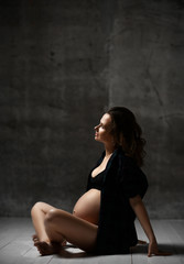 Fototapeta na wymiar Beautiful young pregnant happy mother woman posing in underwear on dark 