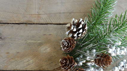 pine spray with silver painted berries and pine cones with painted white on the edges  for snow on a wood background with writing space