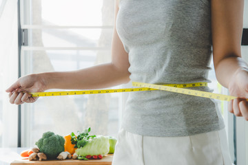 Eat good food for good shape concepts. Woman measuring her body by measure tape have a vegetables...