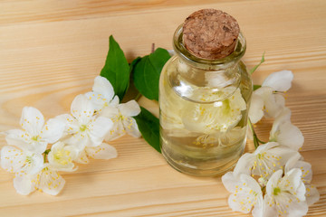 flowers of philadelphus somewhere called jasmine or mock orange and a bottle of oil on a wooden table