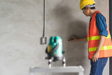 Worker using laser level machine in the renovation room.