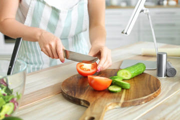 Obraz na płótnie Canvas Young woman making fresh salad in kitchen, closeup