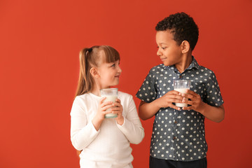 Cute little children with glasses of milk on color background