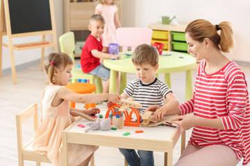 Obraz na płótnie Canvas Nursery teacher with cute little children in kindergarten
