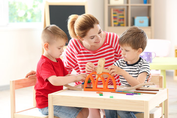 Nursery teacher with cute little children in kindergarten