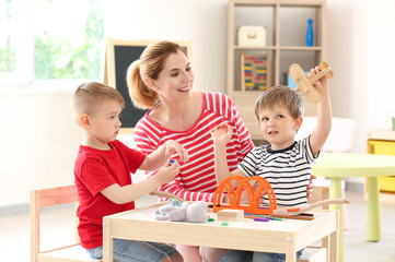 Nursery teacher with cute little children in kindergarten
