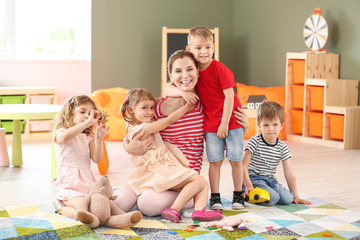 Nursery teacher with cute little children in kindergarten