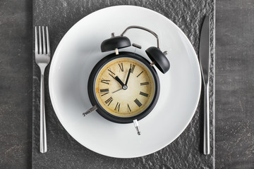 Simple table setting with alarm clock on dark background