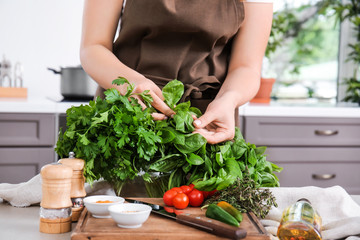 Woman with fresh herbs in kitchen