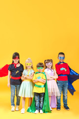 Cute little children dressed as superheroes on color background