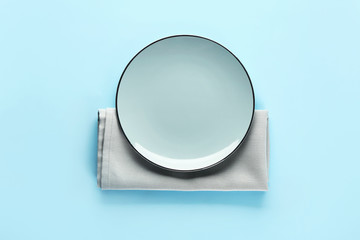Plate and napkin on color background