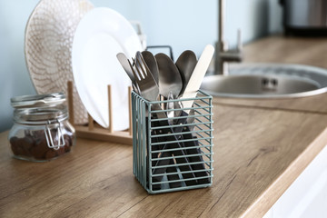 Clean cutlery in holder on table in kitchen