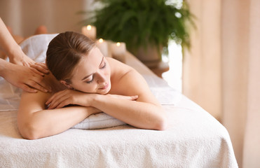 Beautiful young woman receiving massage in spa salon