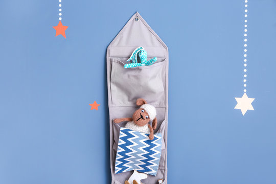 Hanging fabric organizer with child toys on color background