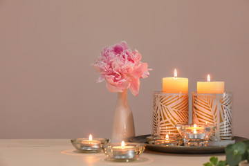 Beautiful burning candles and flowers on table