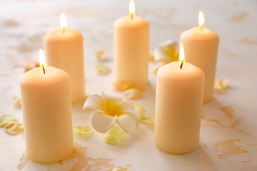 Fototapeta na wymiar Burning candles and beautiful flower petals on table