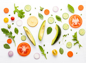 Food pattern with raw ingredients of salad, lettuce leaves, cucumbers, tomatoes, carrots, broccoli, basil ,onion and lemon flat lay on white wooden background.