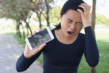 Young Woman screaming in rage with a broken smartphone in her hand