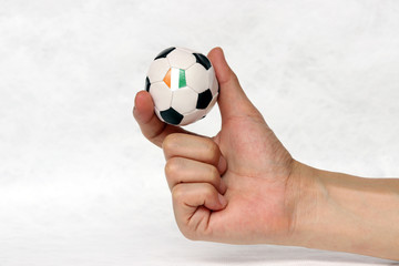 Mini ball of football in hand and one black point of football is Ivory Coast flag, hold it with two finger on white background.