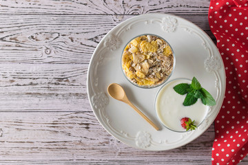 Wooden spoon, bowl of yogurt and bowl of oatmeal in bowl on wooden table. Flat lay.