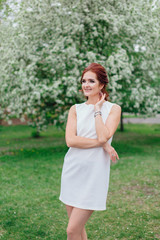 Charming woman wearing beautiful white dress under the apple tree